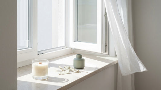 Are candles bad for you: an open casement window with a sheer curtain lifting in daylight beside an unlit candle in clear glass